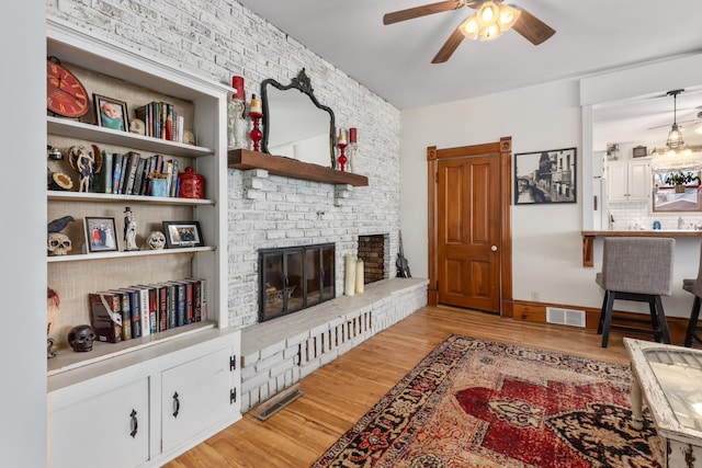 living room featuring a fireplace, visible vents, and light wood-type flooring