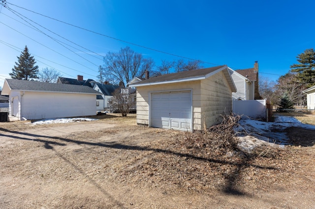 detached garage with dirt driveway and fence