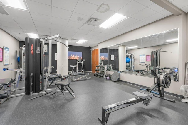 exercise room featuring a paneled ceiling, baseboards, and visible vents