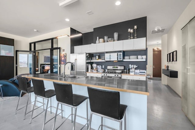 kitchen featuring open shelves, a kitchen bar, white cabinets, a sink, and stainless steel appliances