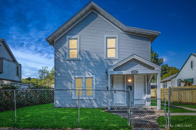 traditional-style home featuring covered porch, a fenced front yard, a gate, and a front lawn