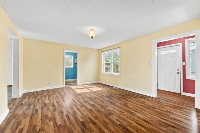 interior space with a textured ceiling, baseboards, and wood finished floors