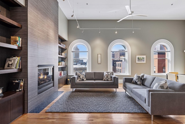 living room featuring built in features, plenty of natural light, wood finished floors, and a tile fireplace