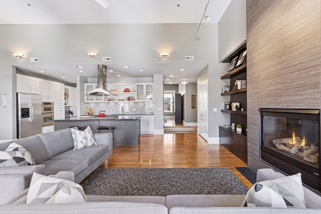 living room featuring built in features, visible vents, light wood-style floors, and a tiled fireplace