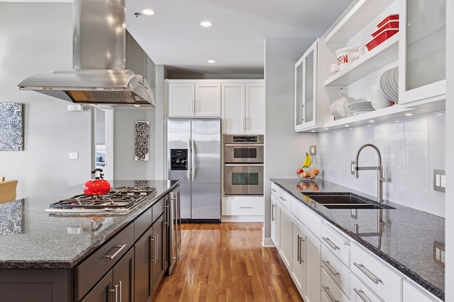 kitchen with light wood-style floors, island range hood, white cabinets, stainless steel appliances, and a sink