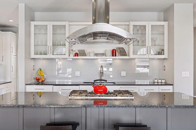 kitchen featuring dark stone counters, white cabinets, and island range hood