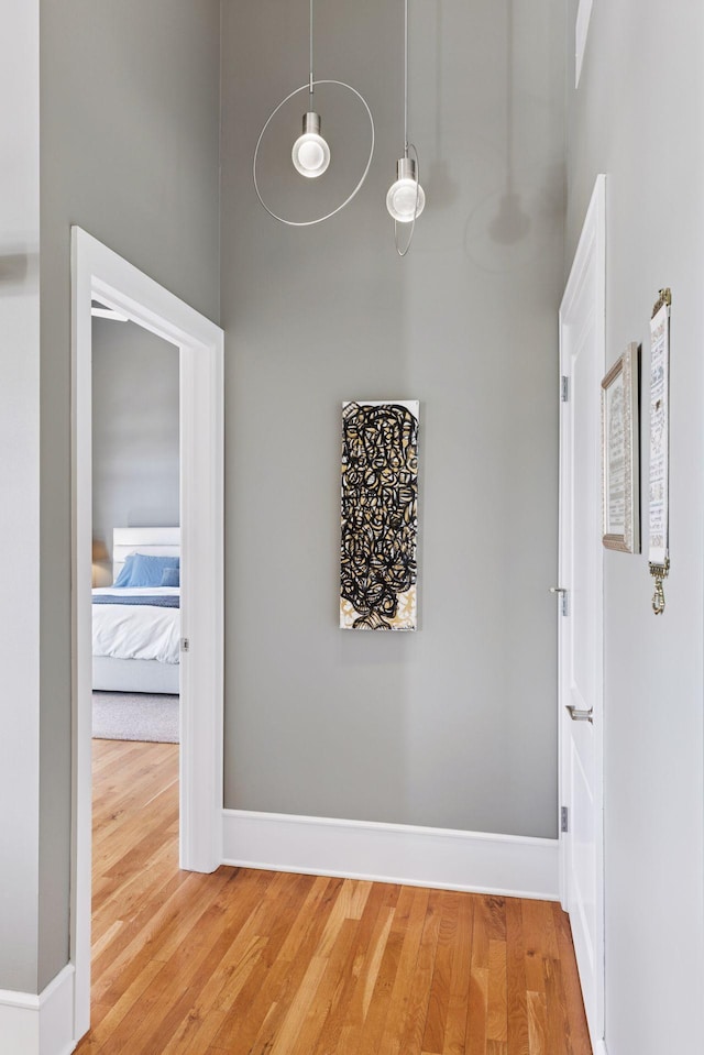 hall featuring baseboards, a high ceiling, and light wood-style floors