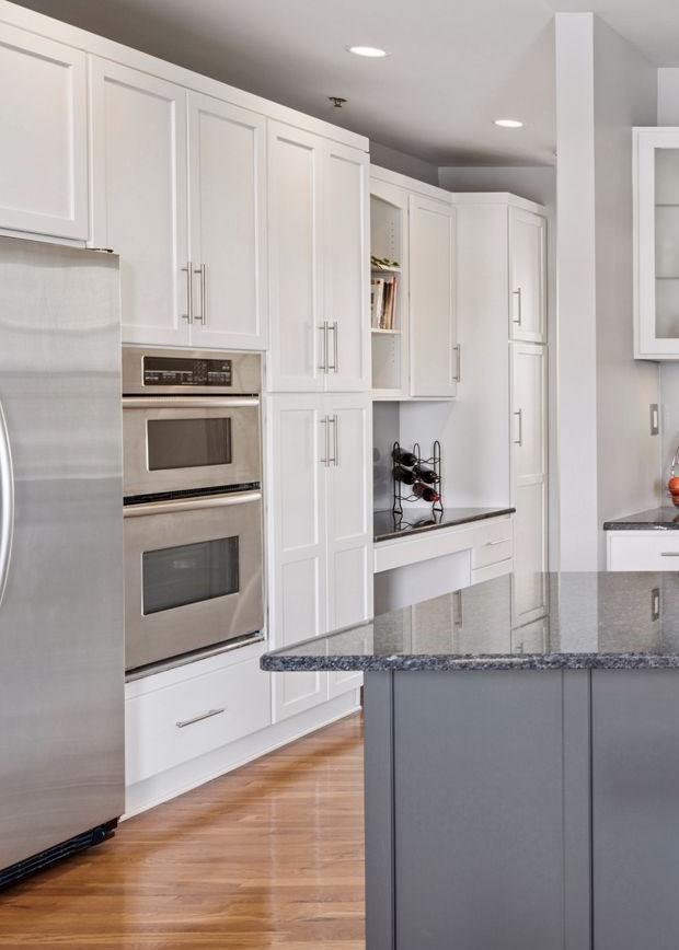 kitchen with dark stone counters, light wood finished floors, appliances with stainless steel finishes, and white cabinetry