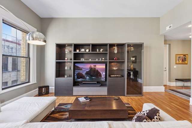 living room with visible vents, baseboards, and wood finished floors