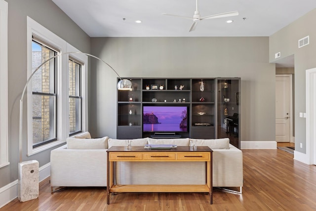 living room with visible vents, a ceiling fan, baseboards, and wood finished floors