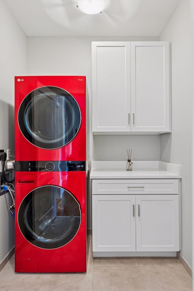 washroom with cabinet space, stacked washing maching and dryer, and baseboards