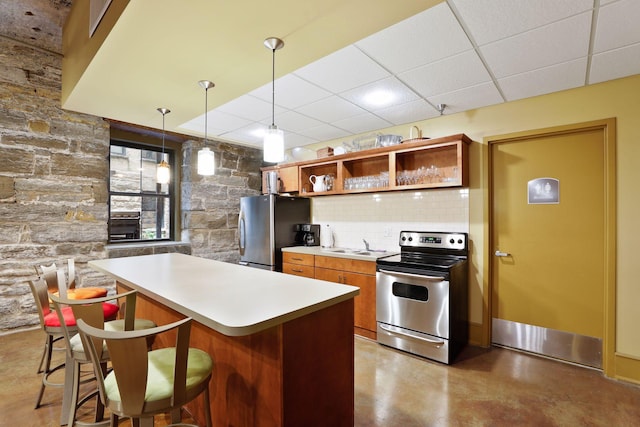 kitchen with backsplash, a drop ceiling, brown cabinets, appliances with stainless steel finishes, and open shelves