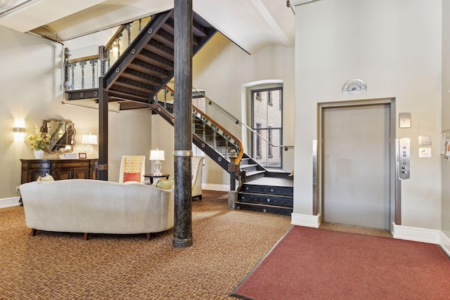 carpeted foyer featuring baseboards, elevator, a towering ceiling, and stairs