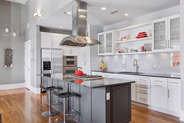 kitchen featuring visible vents, a kitchen island, a sink, appliances with stainless steel finishes, and island range hood