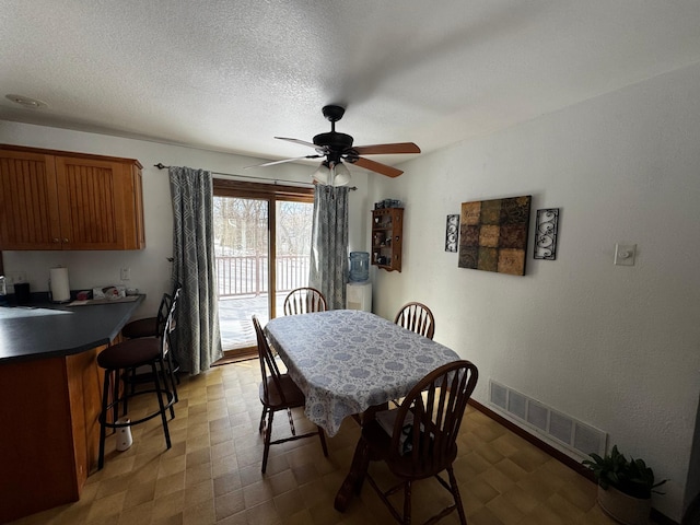 dining room with a ceiling fan, visible vents, a textured ceiling, and tile patterned floors