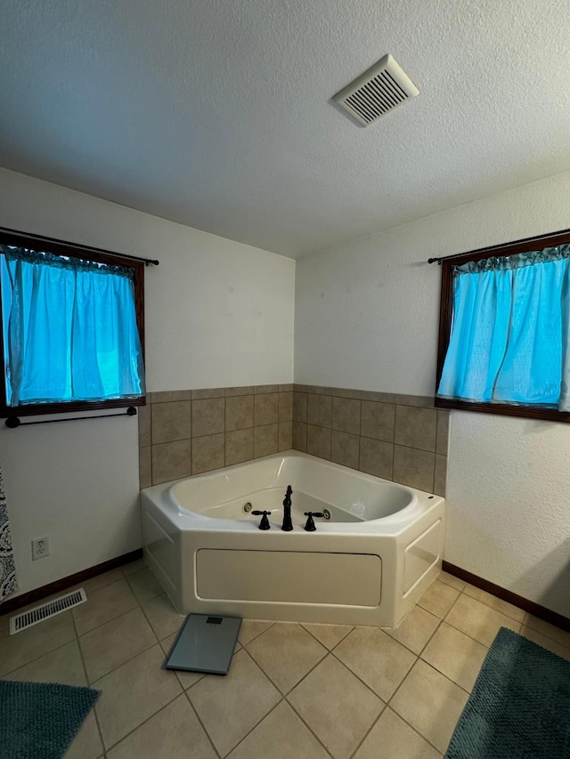 bathroom with tile patterned flooring, visible vents, a textured ceiling, and a whirlpool tub