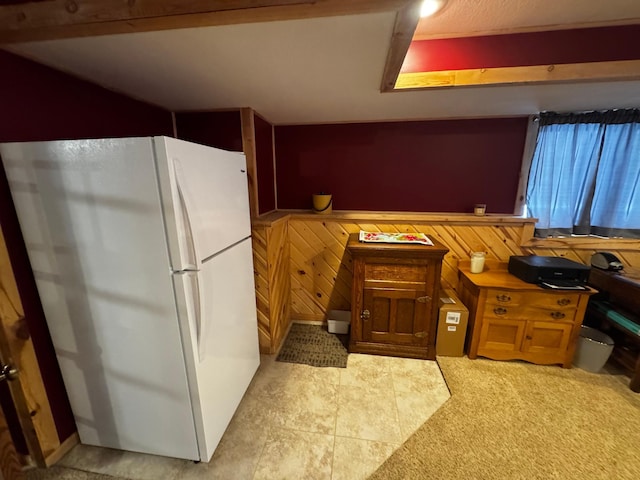 kitchen featuring freestanding refrigerator, a wainscoted wall, and wood walls