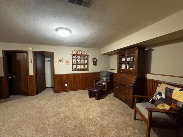 sitting room featuring wood walls, visible vents, a textured ceiling, and wainscoting