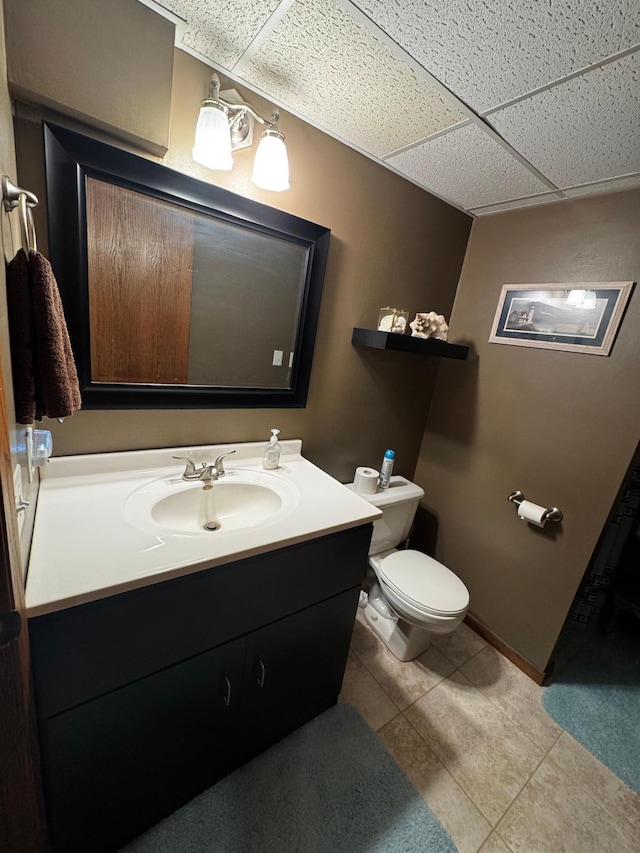 bathroom with toilet, tile patterned floors, a drop ceiling, and vanity