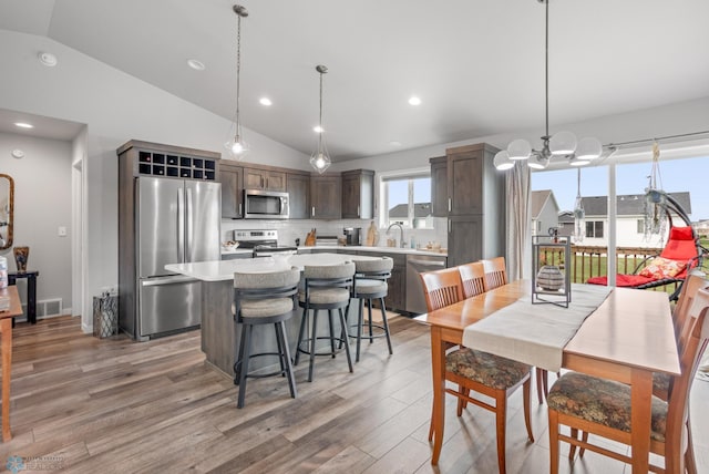 kitchen with a center island, stainless steel appliances, light countertops, visible vents, and light wood-style floors