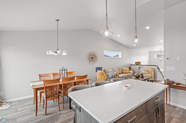 kitchen featuring pendant lighting, an inviting chandelier, vaulted ceiling, light wood-type flooring, and baseboards