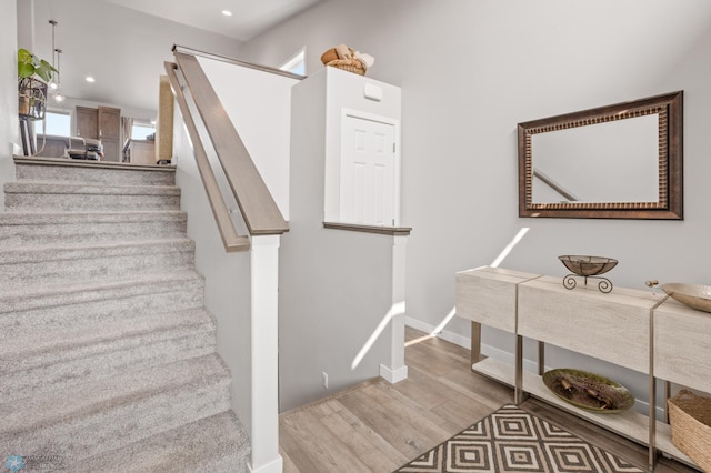 stairway featuring baseboards, wood finished floors, and recessed lighting