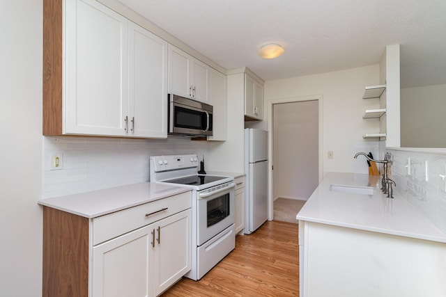 kitchen featuring white cabinets, white appliances, open shelves, and a sink