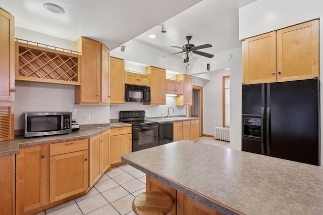 kitchen featuring light tile patterned floors, radiator heating unit, ceiling fan, black appliances, and a sink