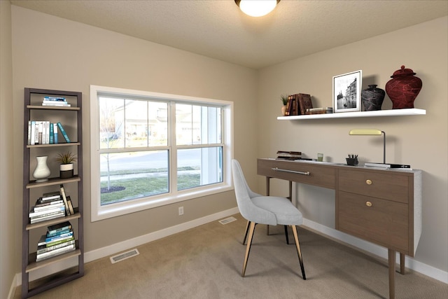 office space with baseboards, a textured ceiling, visible vents, and light colored carpet