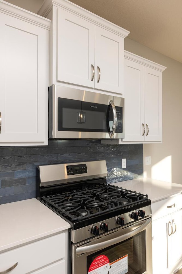 kitchen with white cabinetry, appliances with stainless steel finishes, decorative backsplash, and light countertops