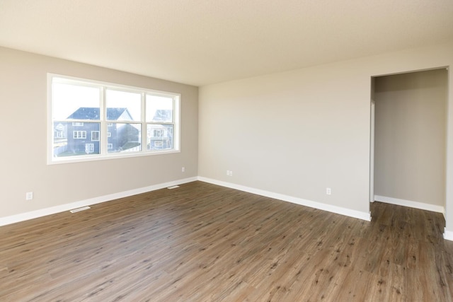 spare room with visible vents, baseboards, and wood finished floors