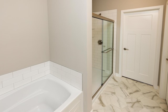 full bathroom featuring marble finish floor, a stall shower, and a garden tub