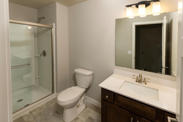 bathroom featuring toilet, a shower stall, baseboards, and vanity