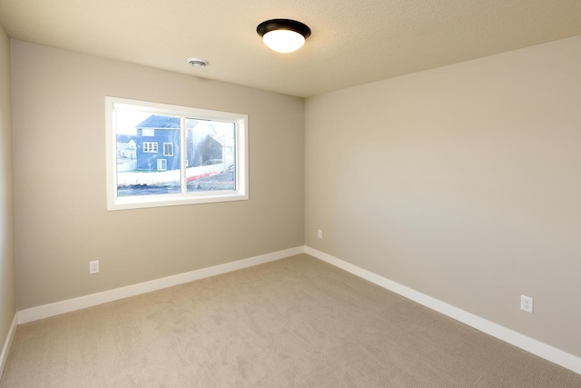 carpeted spare room with a textured ceiling and baseboards