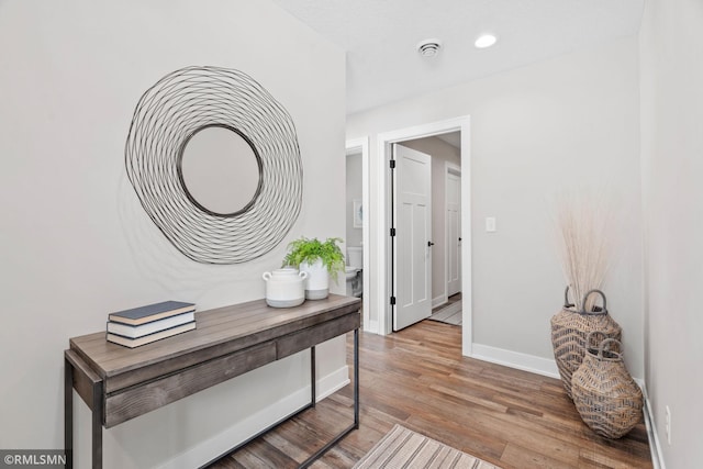 corridor with baseboards, wood finished floors, and recessed lighting