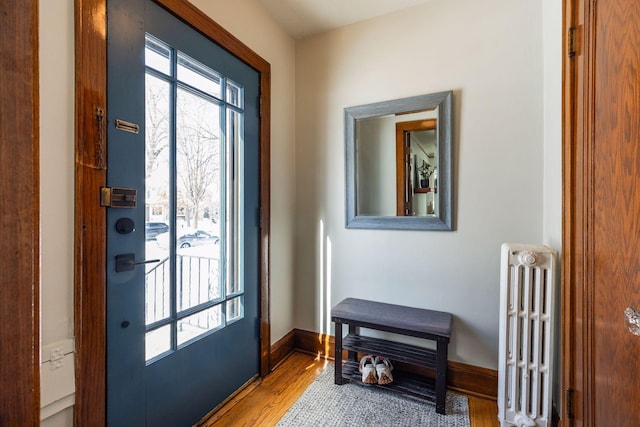 foyer with radiator, a healthy amount of sunlight, baseboards, and wood finished floors