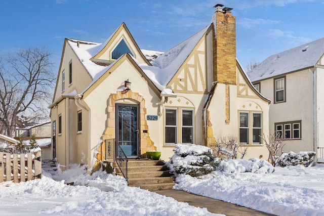 english style home featuring a chimney and stucco siding