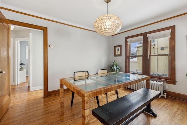 dining area featuring radiator, light wood-style flooring, baseboards, and crown molding