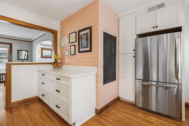 kitchen featuring visible vents, light wood-style floors, freestanding refrigerator, and wallpapered walls