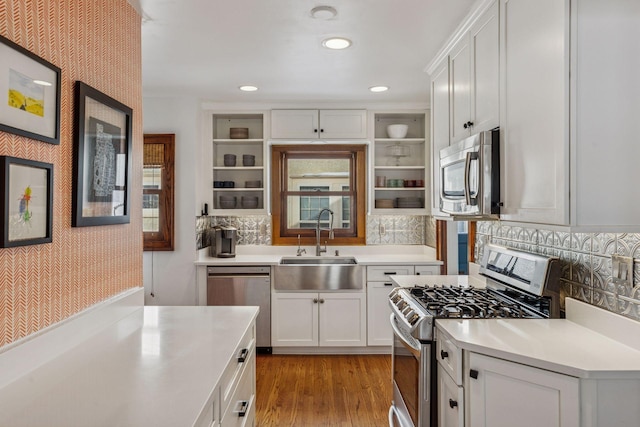 kitchen with wallpapered walls, appliances with stainless steel finishes, light countertops, open shelves, and a sink