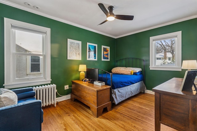 bedroom with ornamental molding, radiator, light wood-style flooring, and baseboards