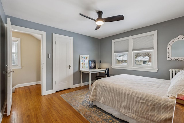 bedroom featuring radiator heating unit, a closet, baseboards, and wood finished floors