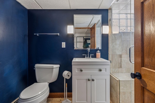 full bathroom with a paneled ceiling, toilet, a shower stall, vanity, and baseboards