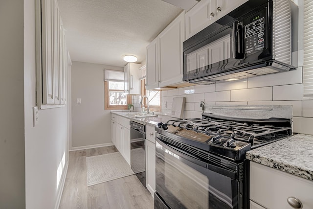 kitchen featuring decorative backsplash, white cabinetry, a sink, and black appliances