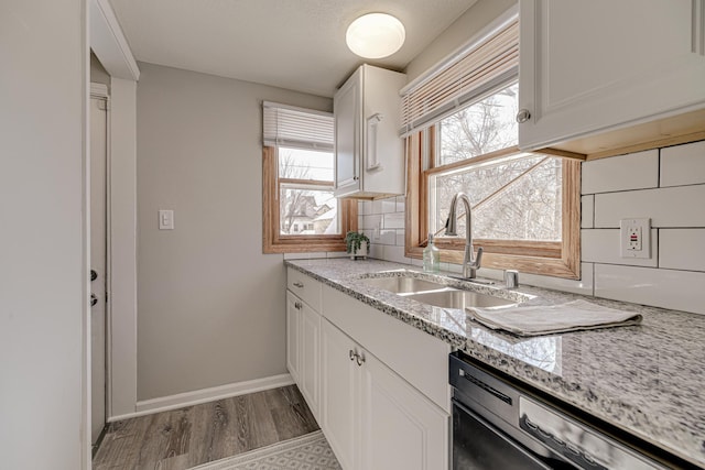 kitchen with backsplash, white cabinetry, a sink, wood finished floors, and dishwasher