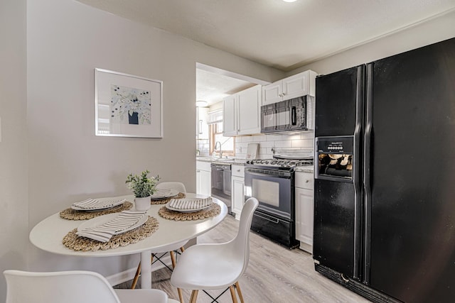 kitchen with light countertops, backsplash, light wood-style floors, white cabinets, and black appliances