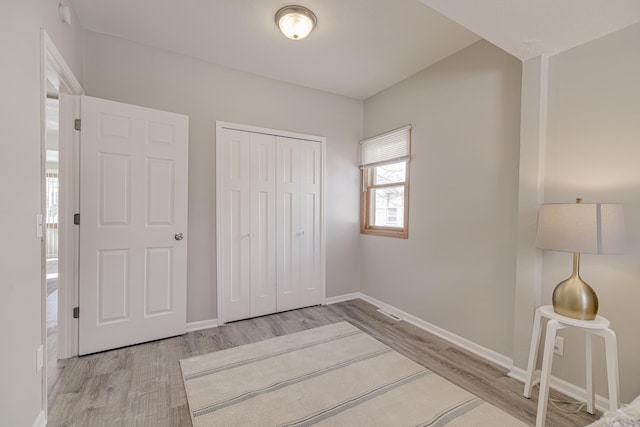 unfurnished bedroom with a closet, wood finished floors, and baseboards