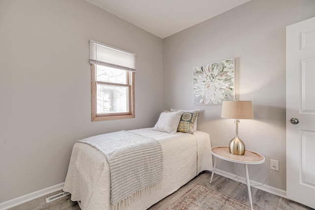 bedroom featuring visible vents, baseboards, and wood finished floors