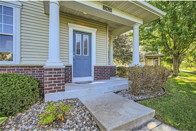 property entrance with brick siding and a porch