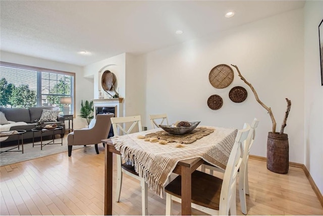 dining area featuring recessed lighting, a fireplace, light wood-style flooring, and baseboards